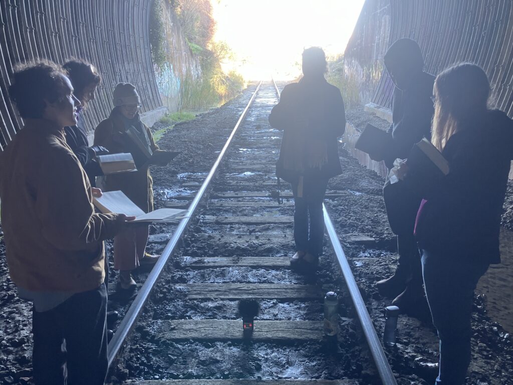 Photo of five singers in a train tunnel.