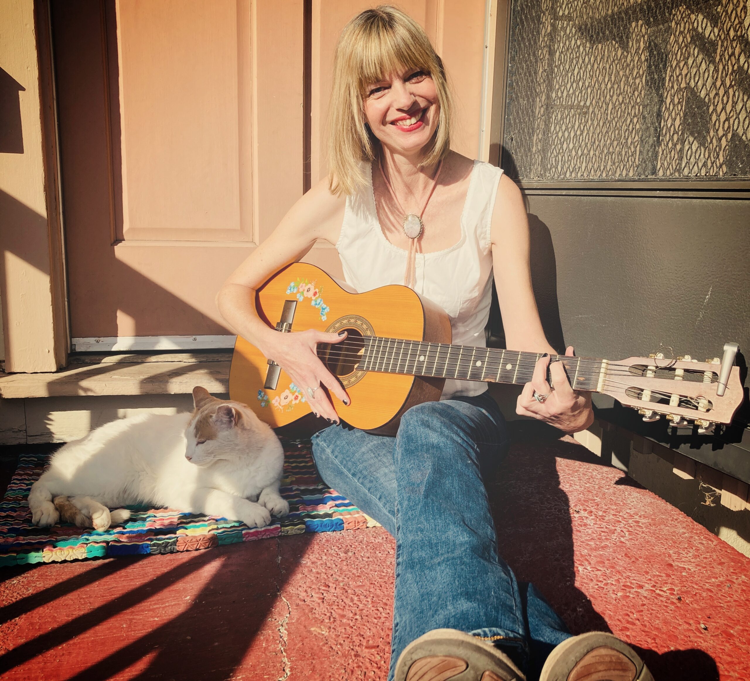A photo of a woman with a guitar and a cat.