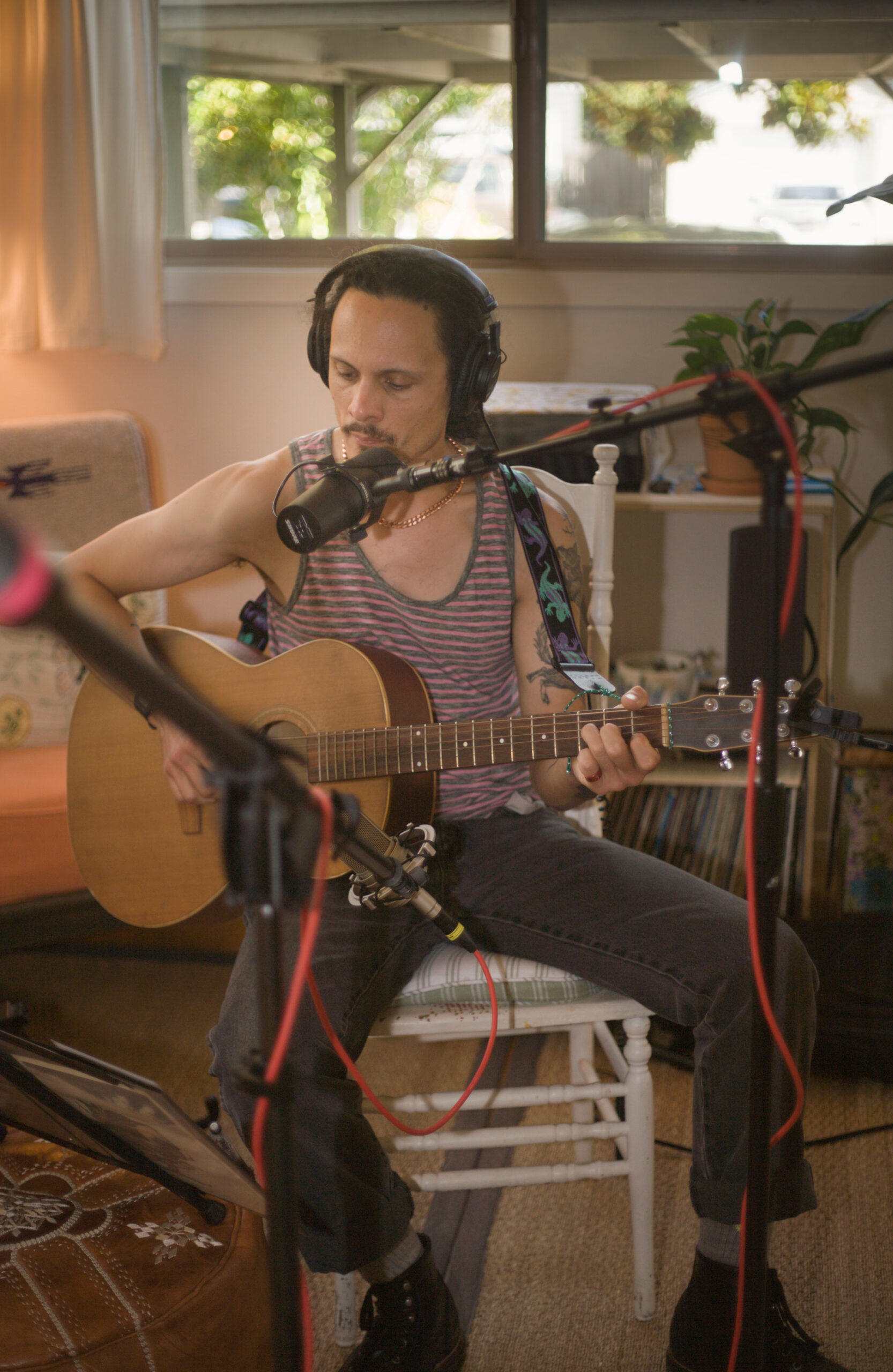 A singer-songwriter with headphones and a guitar warming up for a recording.